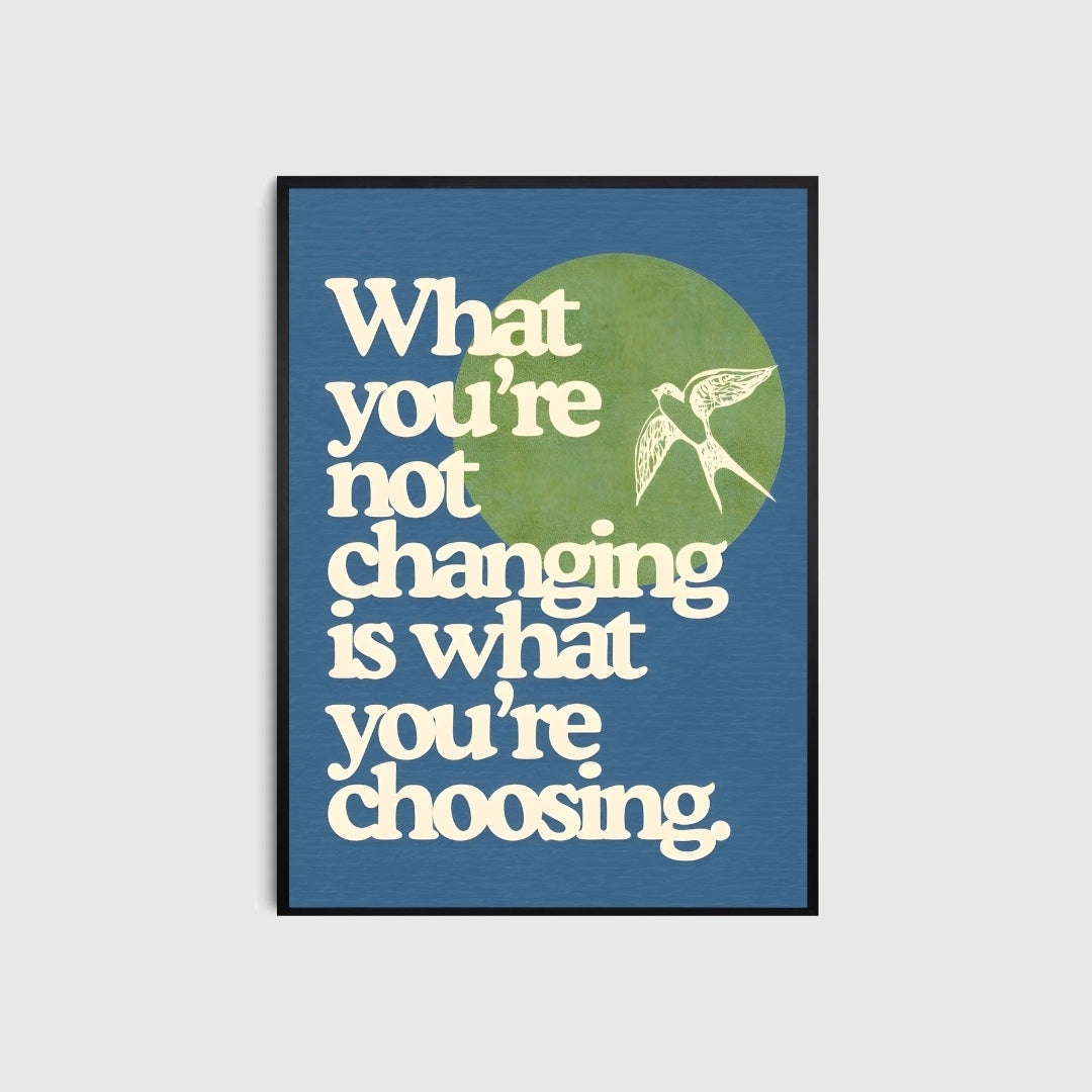 Framed poster with motivational quote 'What you're not changing is what you're choosing' on a blue background.