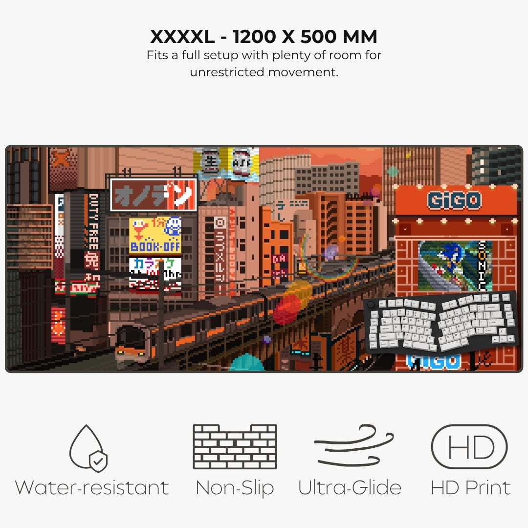 A large rectangular gaming mat shown on a light gray background, with text above reading 'XXXXL - 1200 X 500 MM' and feature icons below for water-resistant, non-slip, ultra-glide, and HD print. The mat features a colorful pixel-art city scene with buildings, signs, and a keyboard graphic.