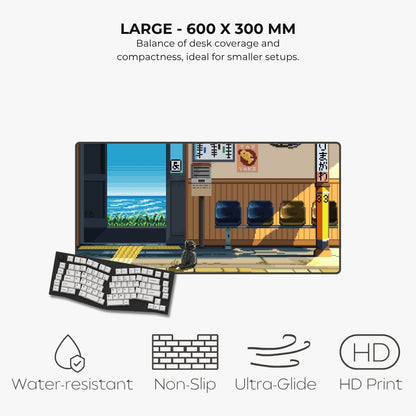 A large desk mat featuring an illustrated train station scene with a cat, shown with a keyboard on top. Text above reads 'LARGE - 600 X 300 MM' and below list features like water-resistant, non-slip, ultra-glide, and HD print.