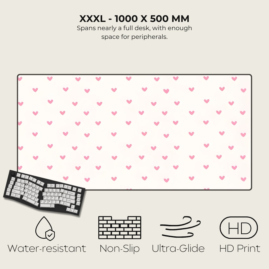 Large desk mat with pink heart pattern, keyboard on the side, and feature icons below.