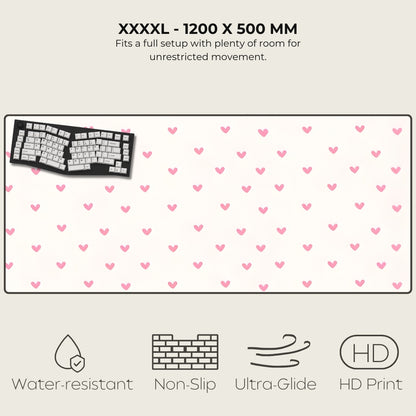 Large desk mat with pink heart pattern, keyboard on left, text and icons at top and bottom.