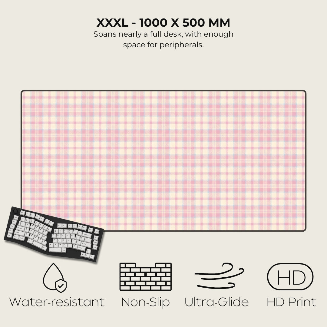 Large desk mat with pink checkered pattern, keyboard on left, text and icons on right.