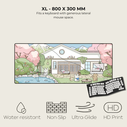 Large mouse pad with a scenic design of a house and cherry blossoms, featuring a keyboard on the side.