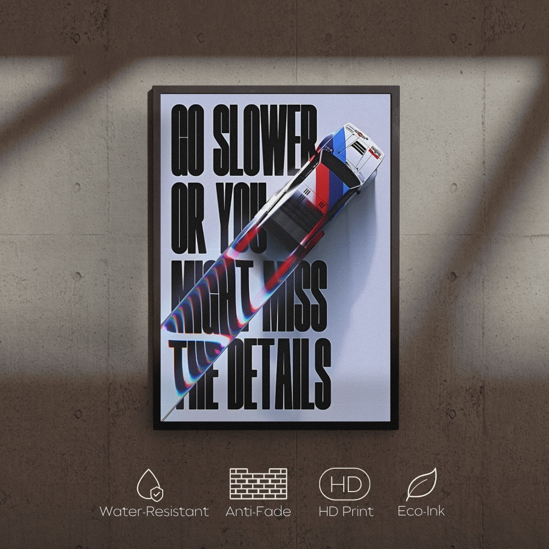 Framed poster with text 'Go slower or you might miss the details' and a car graphic on a textured wall.