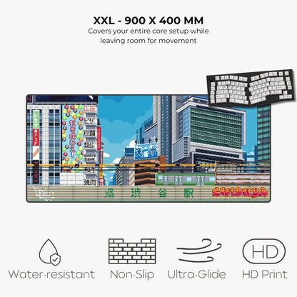 An XXL gaming mouse pad featuring a colorful pixel-art cityscape with Japanese signage and a train, shown on a light gray background with text highlighting its 900 x 400 mm size and features like water resistance, non-slip grip, ultra-glide, and HD print.