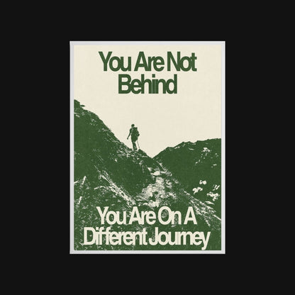 Motivational poster with silhouette of a person on a mountain and text 'You Are Not Behind, You Are On A Different Journey' on a beige background.