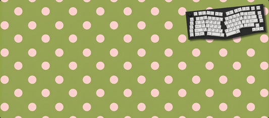 Green desk mat with pink polka dots featuring a keyboard design on a black background