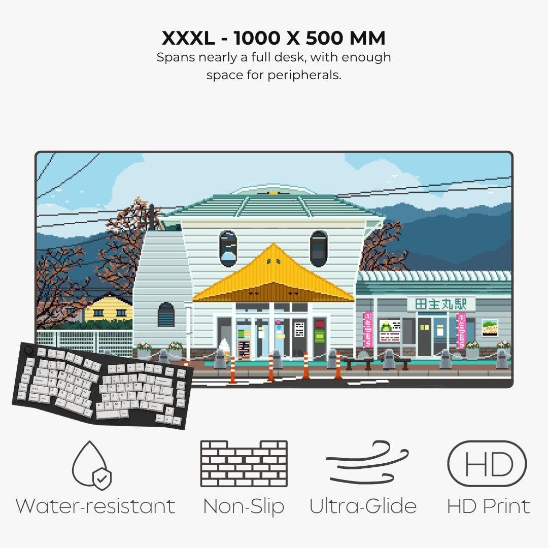 A product infographic for a large desk mat or desk pad featuring a pixel-art illustration of a Japanese street scene. The text at the top reads 'XXXL - 1000 X 500 MM' and describes its size.