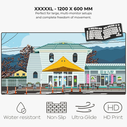 A promotional graphic for a large landscape art print showing a pixel-art style Japanese station building scene. Text at the top reads 'XXXXXL - 1200 X 600 MM' with additional product claims, and icons at the bottom mention water-resistant, non-slip, ultra-glide, and HD print qualities.